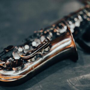 Detailed shot of a saxophone showcasing its shiny brass body against a blurred dark background.